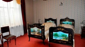 Quarto com cama de casal, uma cadeira, abajur e janela com cortinas.