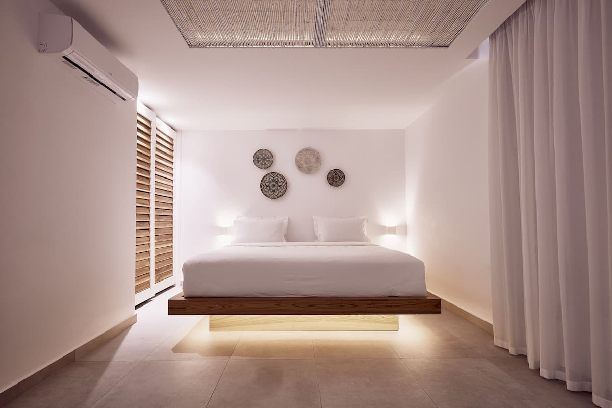 Ein modernes Schlafzimmer mit einem schwebenden Bett, Wandklimaanlage und dekorativen Wandbildern.