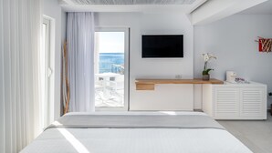 Habitación de hotel moderna con cama, televisión, escritorio y vista al mar.