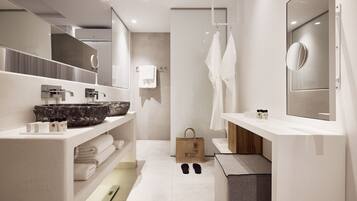 A modern bathroom with a large mirror, two sinks, a bathtub, and a towel rack.