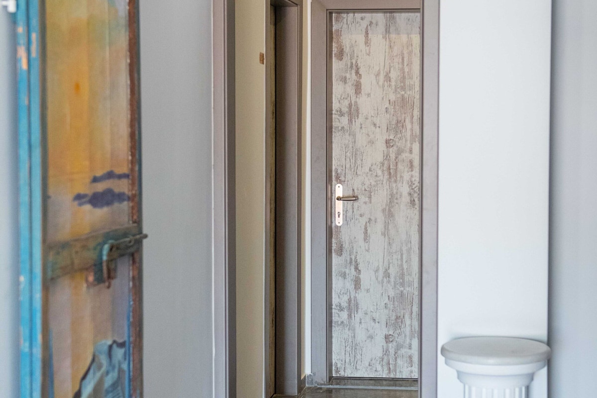 A hallway with a marble floor, a white column, and a door with a distressed wood finish.