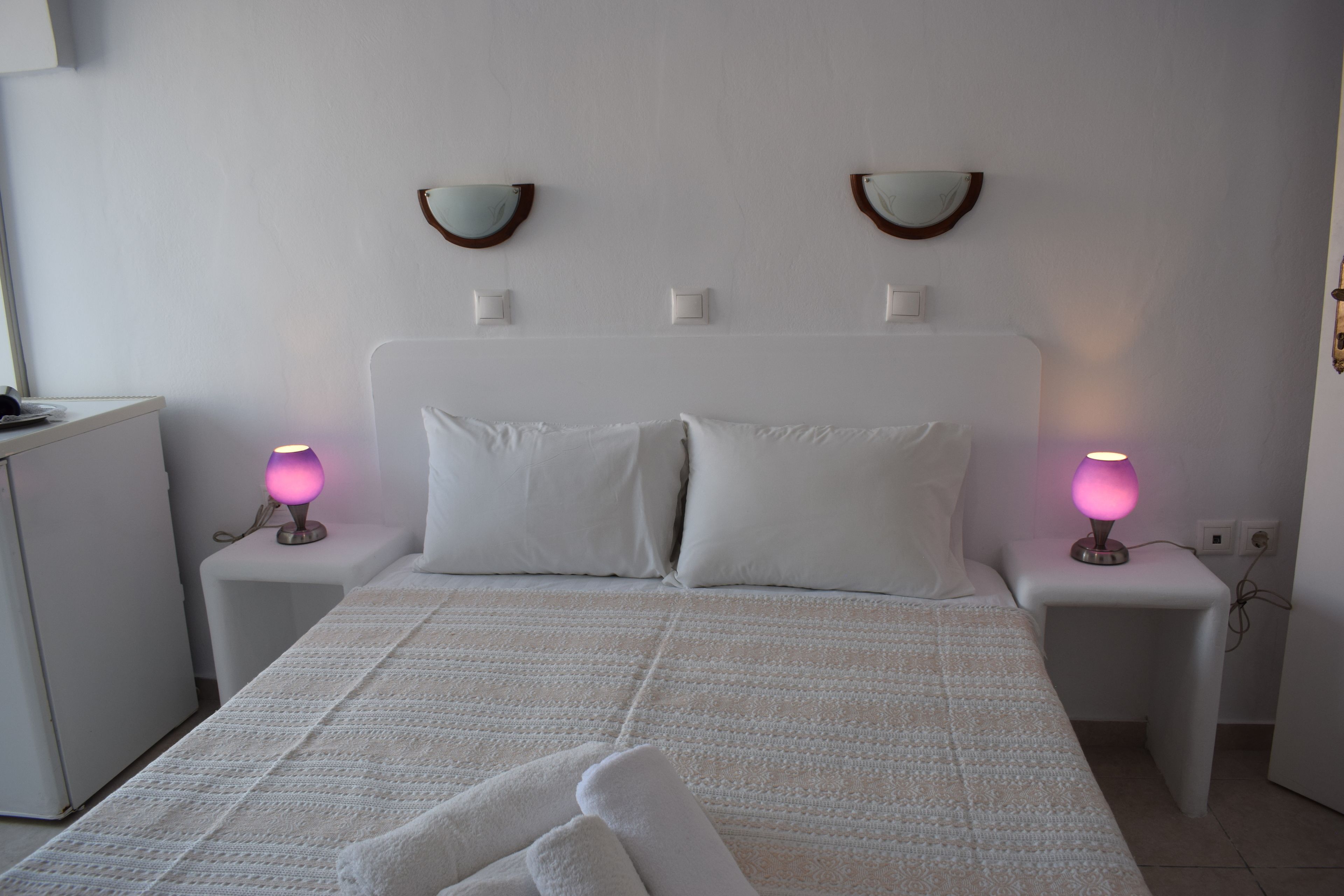 A neatly made bed with white linens, two bedside lamps, and a small bedside table.