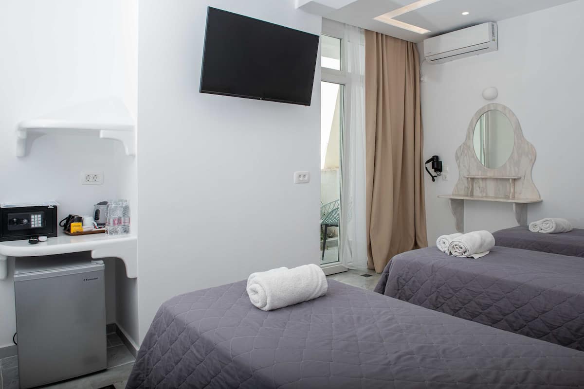A hotel room with two beds, a TV, a mini-fridge, and a desk with a microwave.