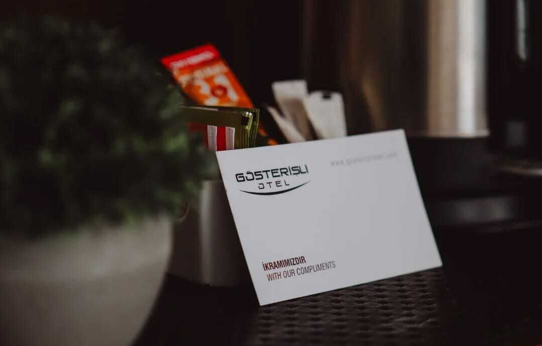 Eine Visitenkarte mit dem Text "GÖSTERISLI HOTEL" und "İKRANİZDIR WITH OUR COMPLIMENTS" auf einem Tisch.