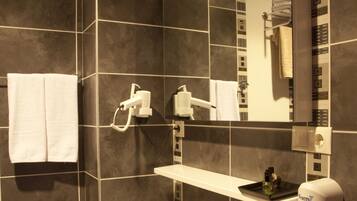 Een moderne badkamer met een grote spiegel, een witte wastafel en een handdoekhouder.