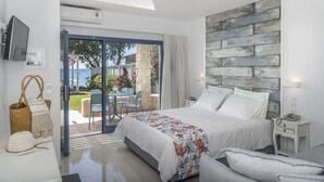 A modern bedroom with a large bed, a TV, and a view of the outdoors. - Kordistos Hotel (Kos)