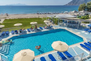 Una piscina al aire libre, sombrillas, sillones reclinables de piscina