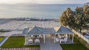 A beachside gazebo with outdoor seating, a pool area with umbrellas, and a view of the sea. - Kordistos Hotel (Kos)