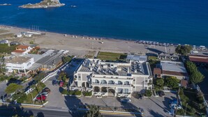 An aerial view of a coastal hotel with a parking lot, beach access, and a view of the sea and a small island. - Kordistos Hotel (Kos)