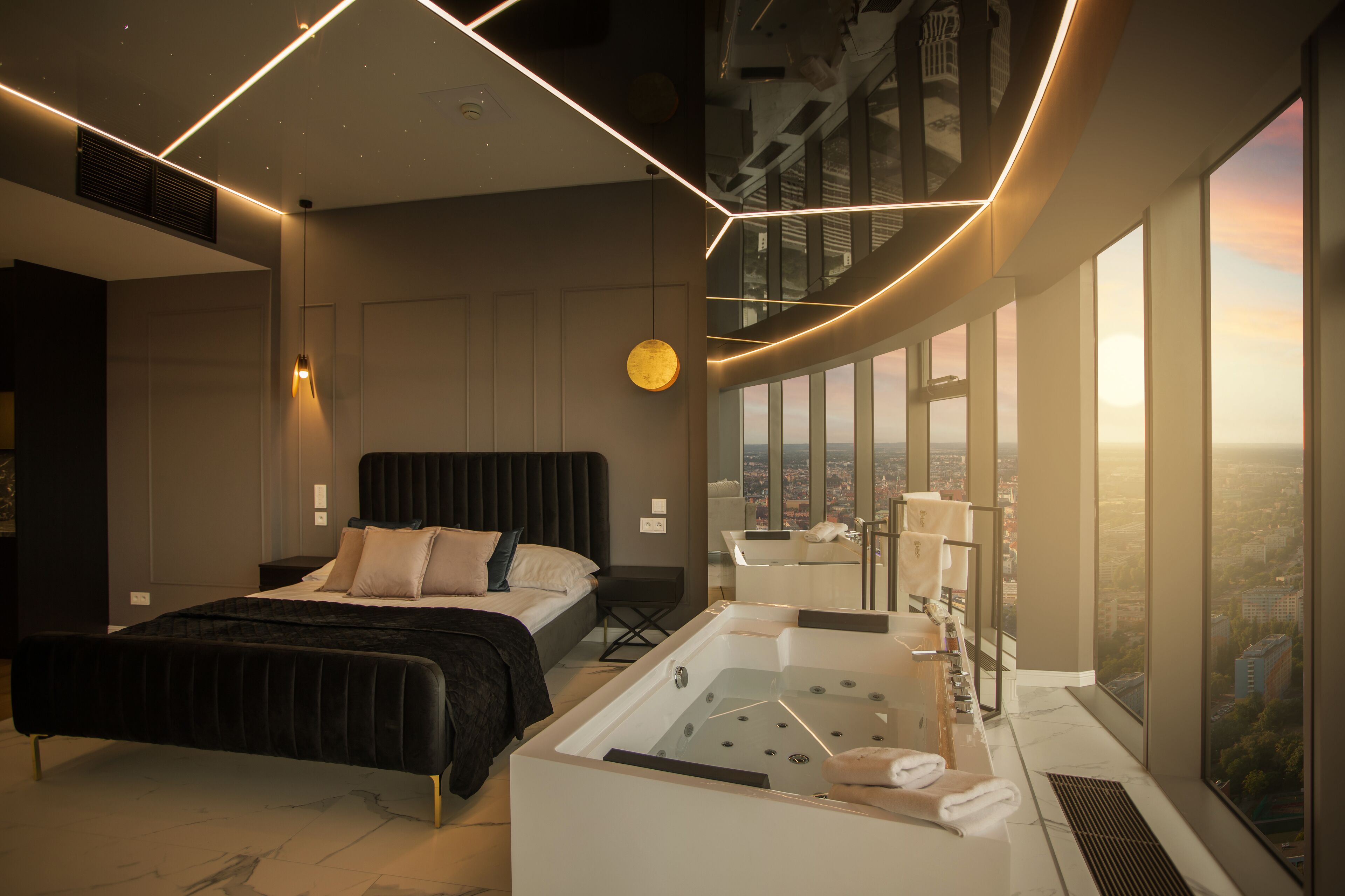 A modern bedroom with a large bed, a bathtub, and a city view.