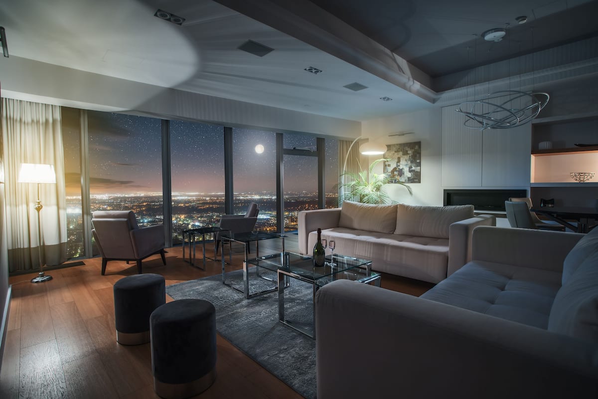 Ein modernes Wohnzimmer mit Stadtblick, einem Glastisch und einer Couch.
