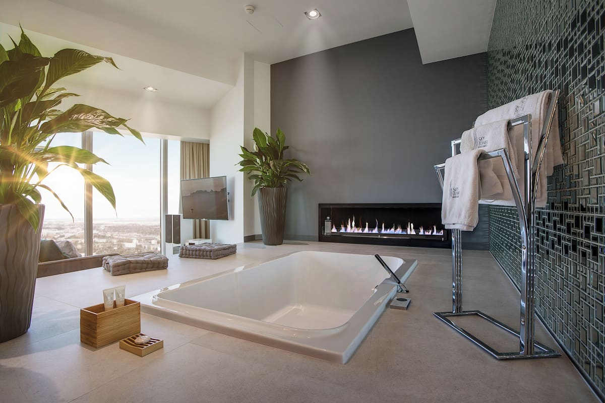 Ein modernes Badezimmer mit einer großzügigen Badewanne, einem Kamin und Blick auf die Stadt.