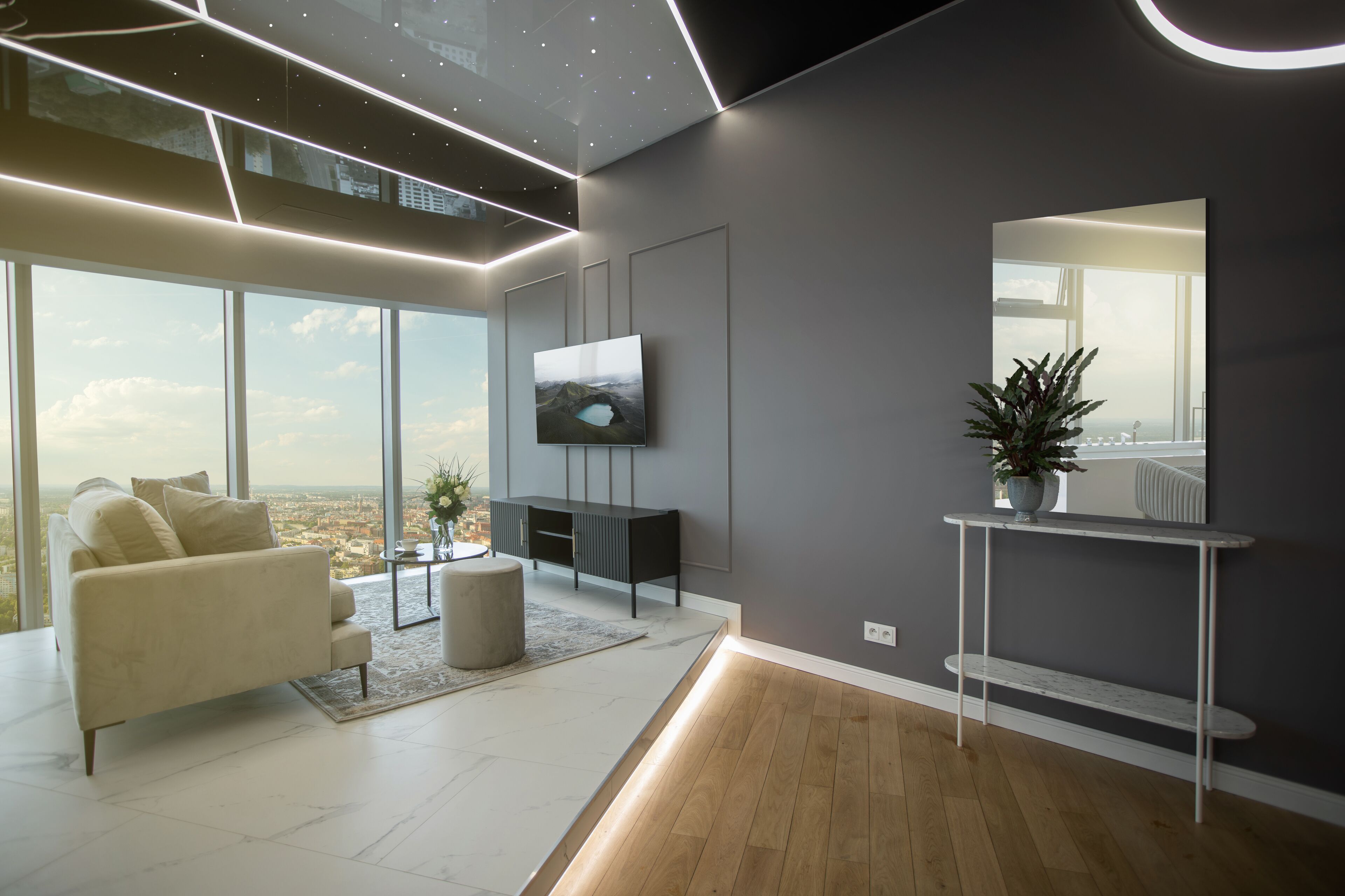 Een moderne woonkamer met een groot raam, een bank, een salontafel en een televisie op een zwart dressoir.