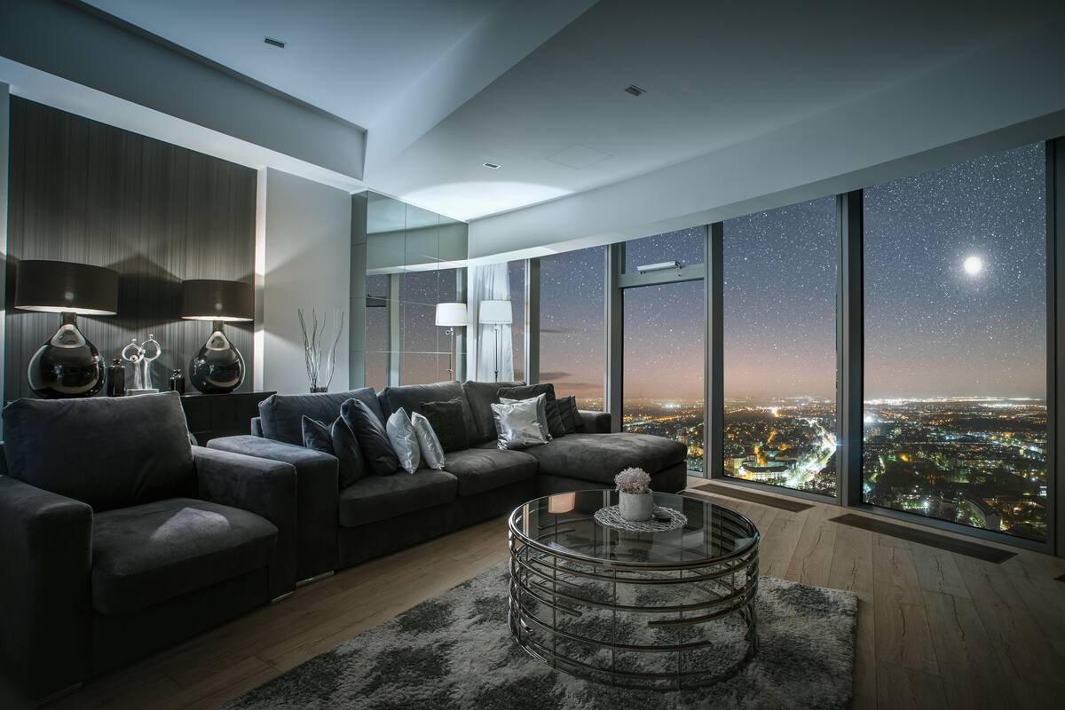 Ein modernes Wohnzimmer mit einem großen Fenster, das einen nächtlichen Blick auf die Stadt bietet.