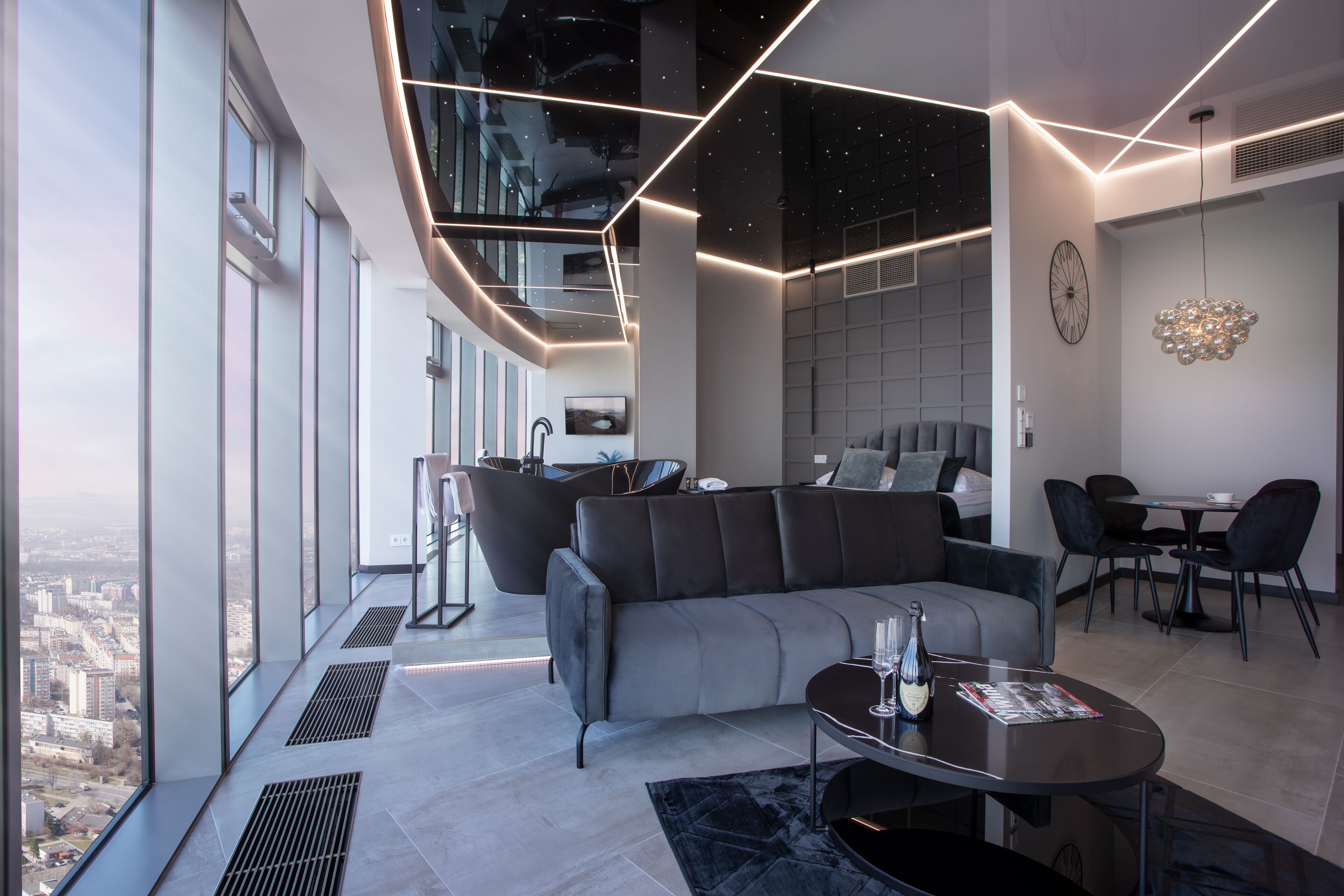 Una sala de estar moderna con un sofá seccional gris, una mesa de centro y un comedor con sillas y una mesa.