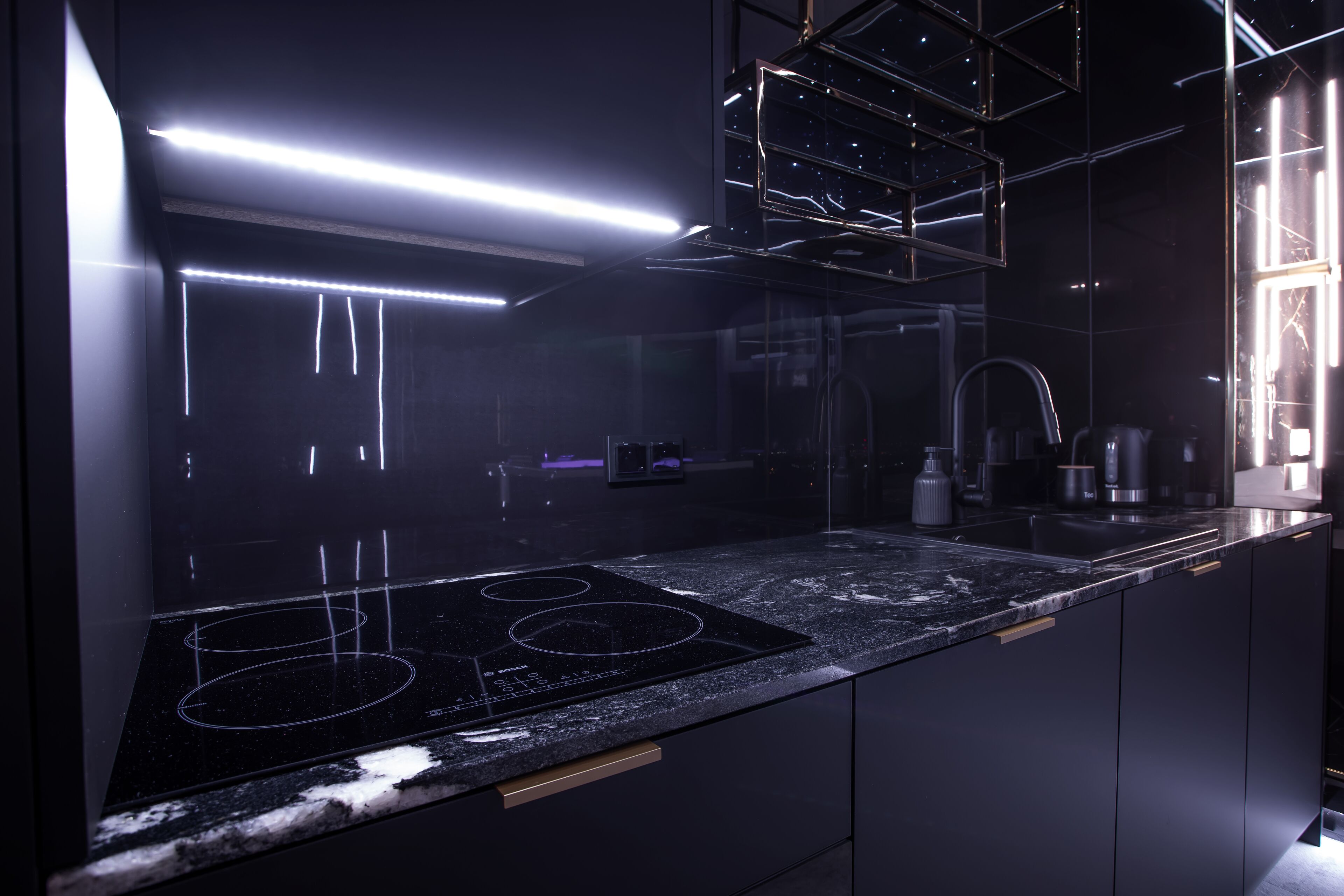 A modern kitchen with a black countertop, stainless steel appliances, and a glass backsplash.