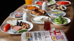 A breakfast table with various food items, a glass of orange juice, and a newspaper. - Saban Acikgoz Hotel (Edirne)