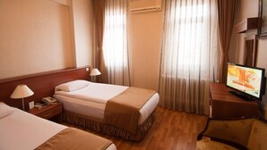 A hotel room with two beds, a TV, a desk with a lamp, and curtains. - Saban Acikgoz Hotel (Edirne)