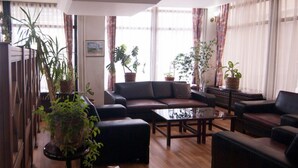 A living room with a sofa set, a coffee table, and several potted plants. - Saban Acikgoz Hotel (Edirne)
