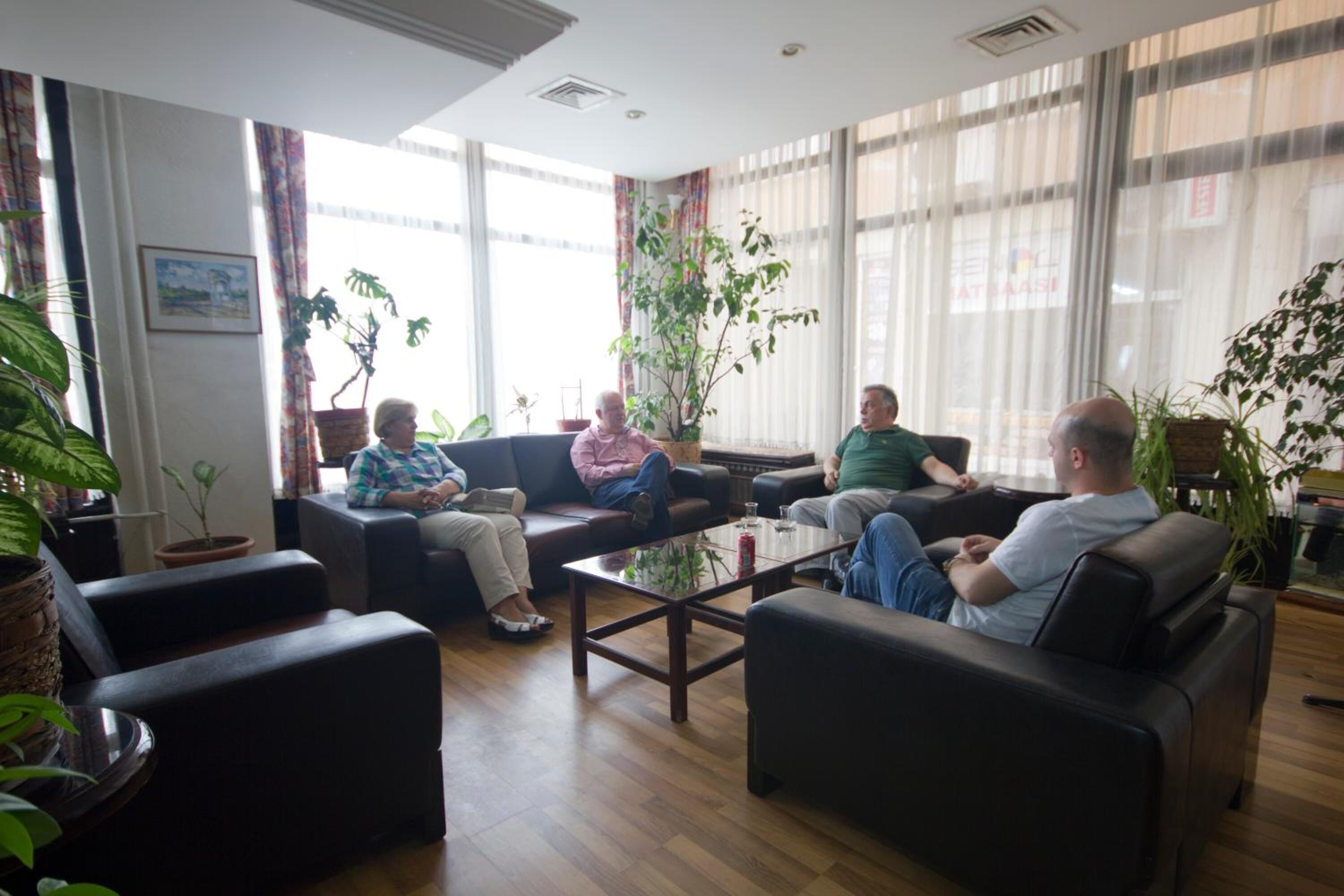 A spacious living area with leather sofas, a coffee table, and potted plants.