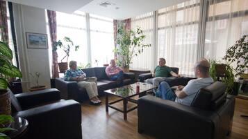 A spacious living area with leather sofas, a coffee table, and potted plants.