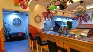 Een bar met een houten toonbank, zwarte barkrukken en een klok aan de muur.