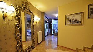 A hallway with a large ornate mirror, wall sconces, and a framed historical photograph. - Ada Life (Eskisehir)