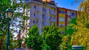 A multi-story building with balconies, surrounded by green trees and a small flower bed. - Ada Life (Eskisehir)