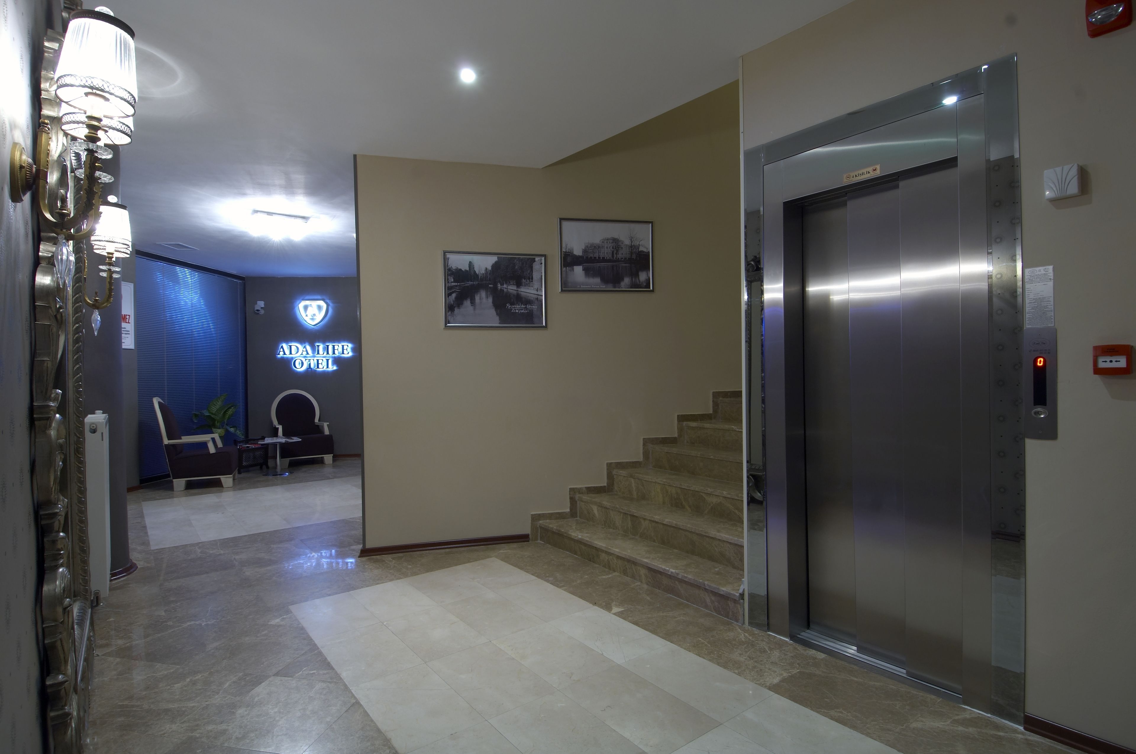 A hotel lobby with a reception desk, seating area, and an elevator.