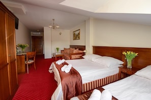 A hotel room with a large bed, a desk, a chair, and a small table.