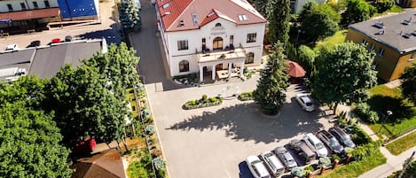A hotel with a central courtyard, surrounded by parked cars and greenery.