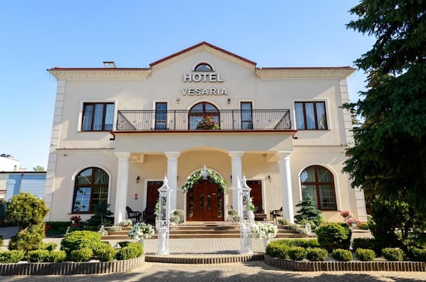 A two-story hotel with a prominent entrance, arched windows, and a balcony with railings.