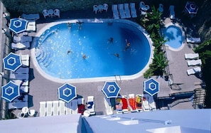 Une vue aérienne d’une piscine entourée de chaises longues et de parasols.