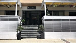 A building entrance with a sign reading "Mimosa Suites," flanked by white columns and potted plants. - Mimosa Suites (Rhodes)