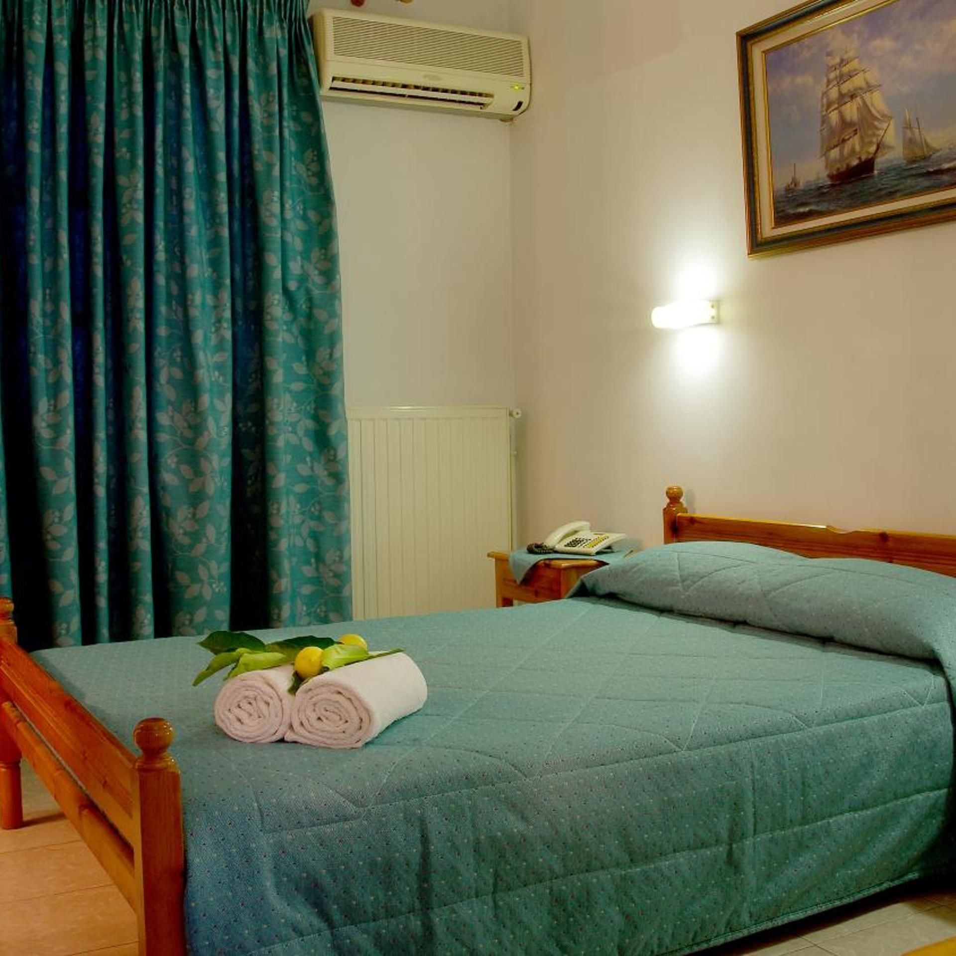 Una habitación con una cama, un cuadro en la pared y una ventana con cortinas.