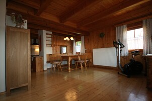 Un interior de madera con una mesa de comedor y sillas, un radiador y una bicicleta estática.