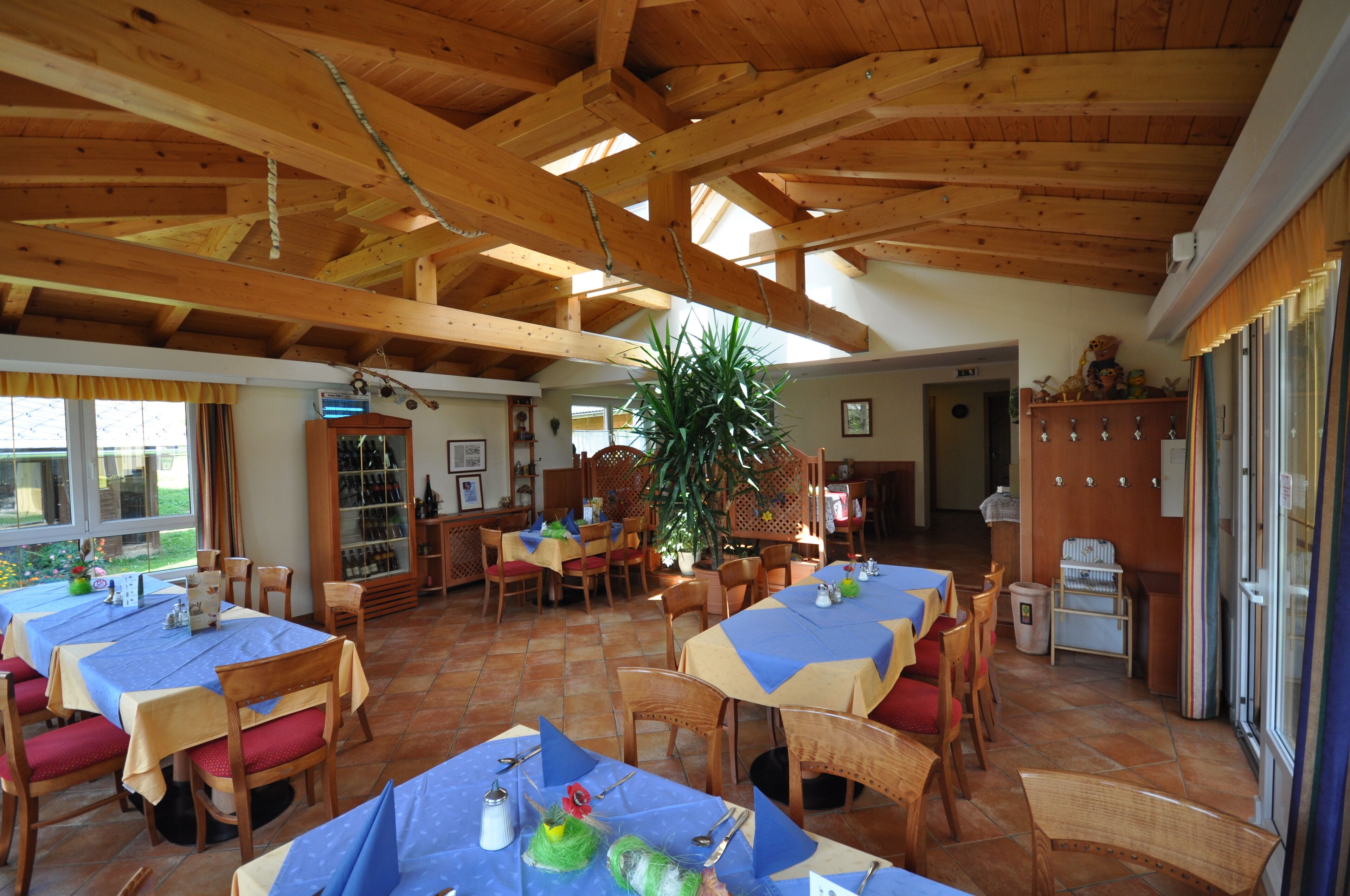 Ein Restaurant mit Holzbalken, Fliesenböden und gedeckten Tischen.