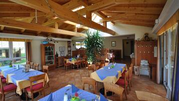 Ein Restaurant mit Holzbalken, Fliesenböden und gedeckten Tischen.