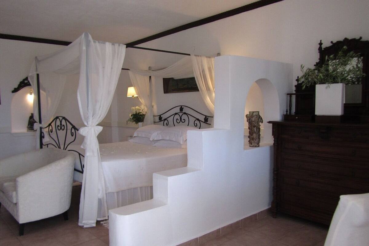 Un dormitorio con cama, una silla, una mesita de noche y un aparador.