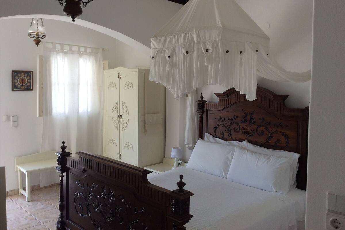 Un dormitorio con cama a dosel, armario, mesita de noche y lámpara colgante.