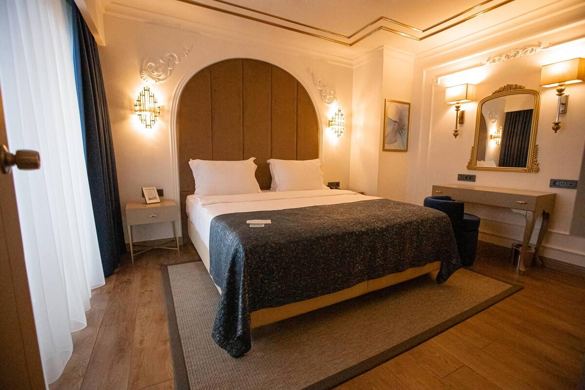 Ein Hotelzimmer mit einem großen Bett, einem Nachttisch, einem Schreibtisch und einem Spiegel.