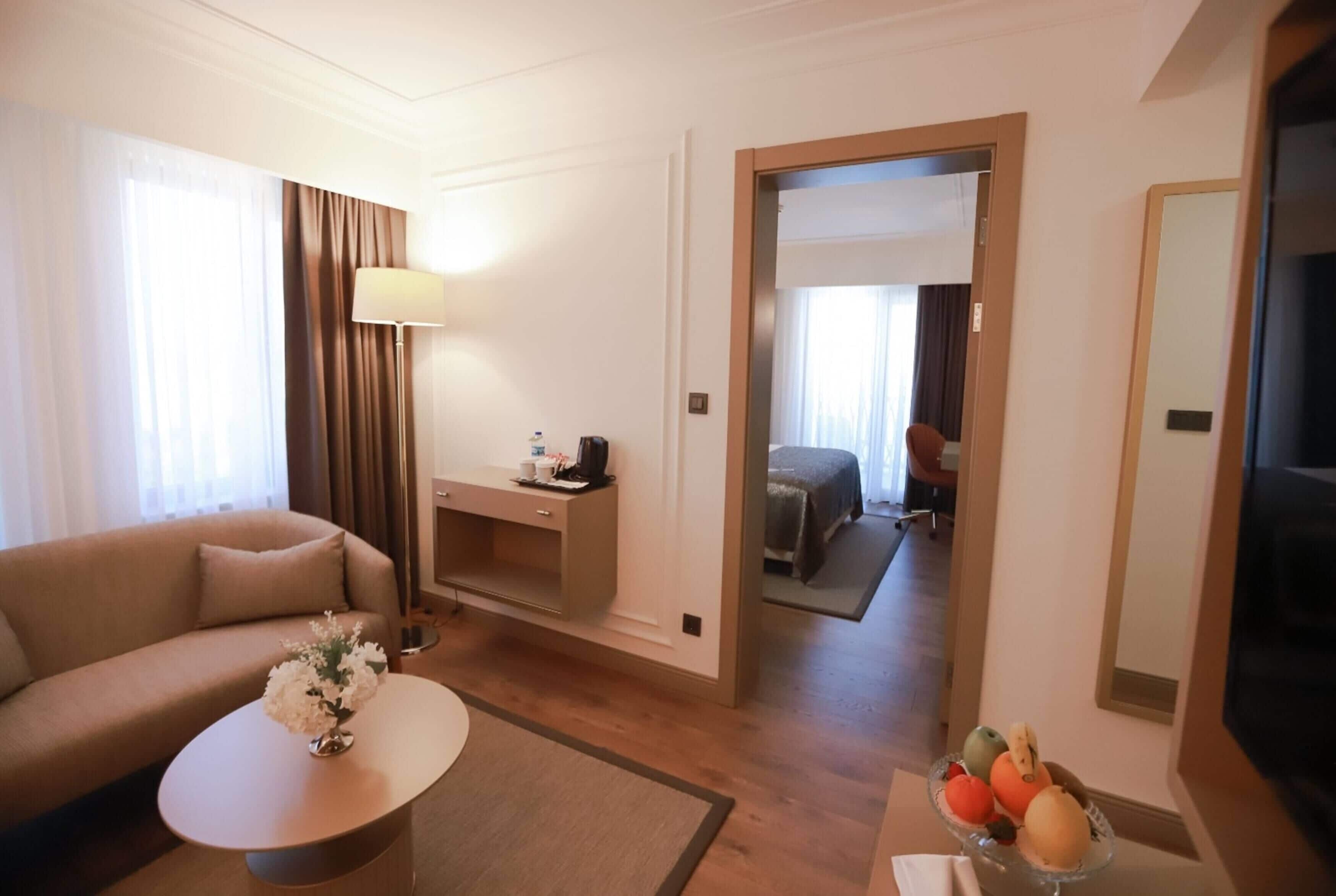 A hotel room with a sofa, a desk, a coffee table, a mirror, and a bed.