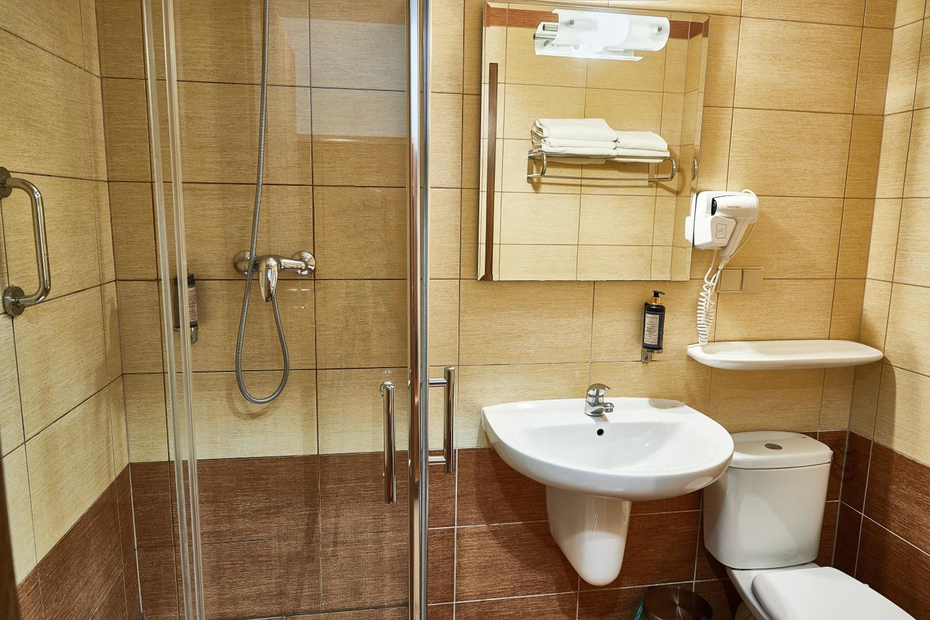 Une salle de bain avec une douche à parois de verre, un lavabo, des toilettes et un porte-serviettes avec des serviettes.