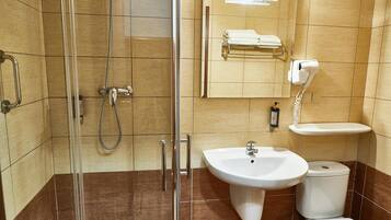 Une salle de bain avec une douche à parois de verre, un lavabo, des toilettes et un porte-serviettes avec des serviettes.
