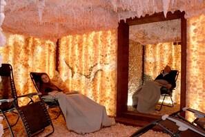Una habitación con pared de piedra, un espejo grande y dos sillones reclinables.