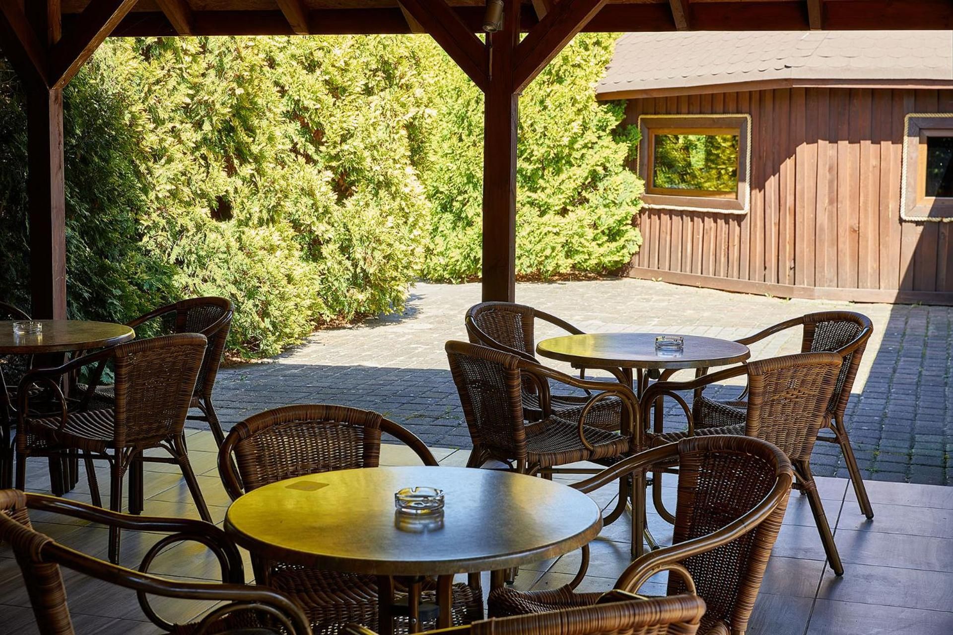 An outdoor patio with wicker furniture and a wooden pergola.