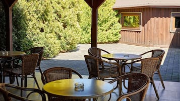 An outdoor patio with wicker furniture and a wooden pergola.