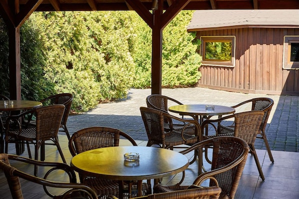 Un patio al aire libre con mobiliario de mimbre y una pérgola de madera.