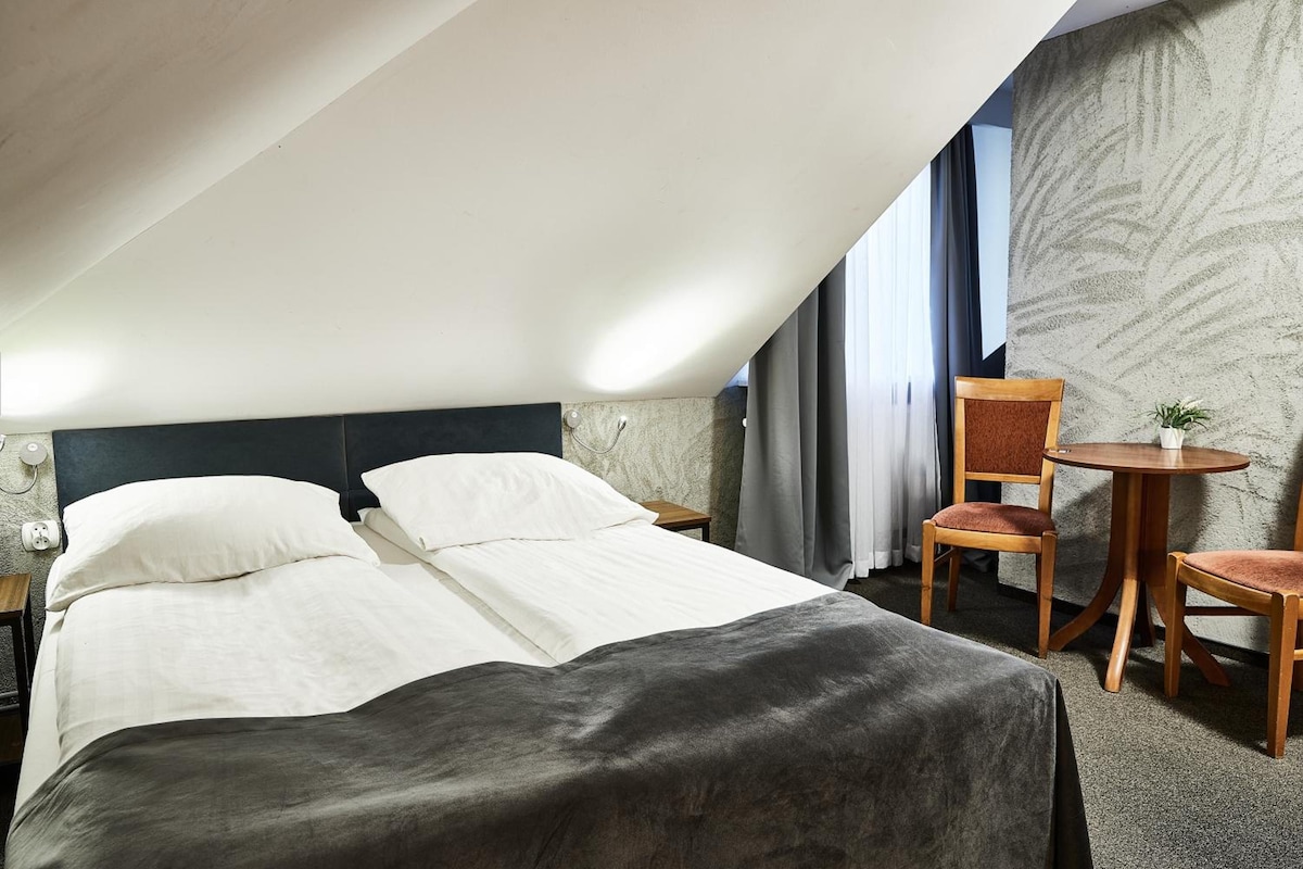Habitación de hotel con cama, una silla, una mesita y una pared con un patrón texturizado.