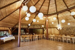 A rustic wooden hall with a high ceiling, multiple tables and chairs, and hanging spherical light fixtures. - Hotel Baranowski (Slubice)